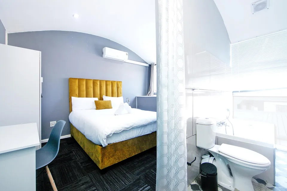 Double bed with yellow headboard next to the en-suite bathroom